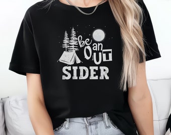 May include: Black t-shirt with a white graphic design featuring a tent, trees, moon, and the words "be an OUT SIDER". The design has a camping theme.