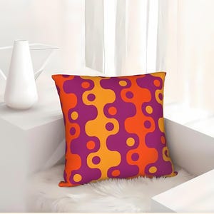 May include: Square throw pillow with a vibrant abstract pattern in shades of orange, purple, and yellow. The pillow features a repeating wavy design with circular accents, creating a bold and colorful decorative accent.