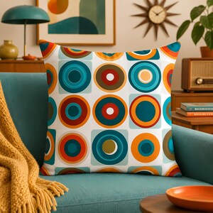 May include: A square throw pillow featuring a repeating pattern of concentric circles in shades of teal, orange, red, and yellow on a white background. The design consists of multiple circular rings layered within each other, creating a geometric motif.