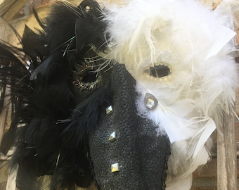 May include: A black and white masquerade mask with feathers and rhinestones. The mask is made of leather and has a long, pointed nose.
