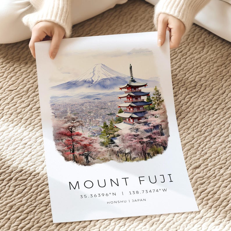 以下が含まれることがあります： 雪が積もった富士山と、手前に赤い五重塔が描かれた水彩画。五重塔は桜の花に囲まれている。画像の下部には黒い文字で「MOUNT FUJI」と、その下に「35.36396&deg;N | 138.73474&deg;W」と「HONSYU | JAPAN」の文字が書かれている。
