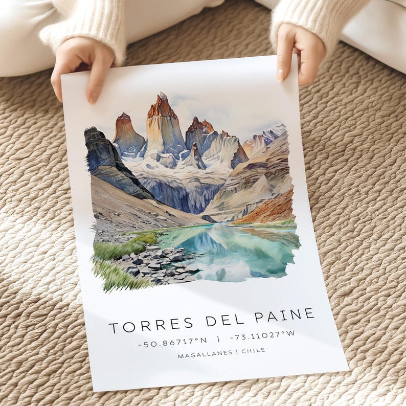 May include: A watercolor painting of the Torres del Paine National Park in Chile. The painting depicts a mountain range with snow-capped peaks and a turquoise lake in the foreground. The text "TORRES DEL PAINE -50.86717&deg;N | -73.11027&deg;W MAGALLANES | CHILE" is printed below the image.
