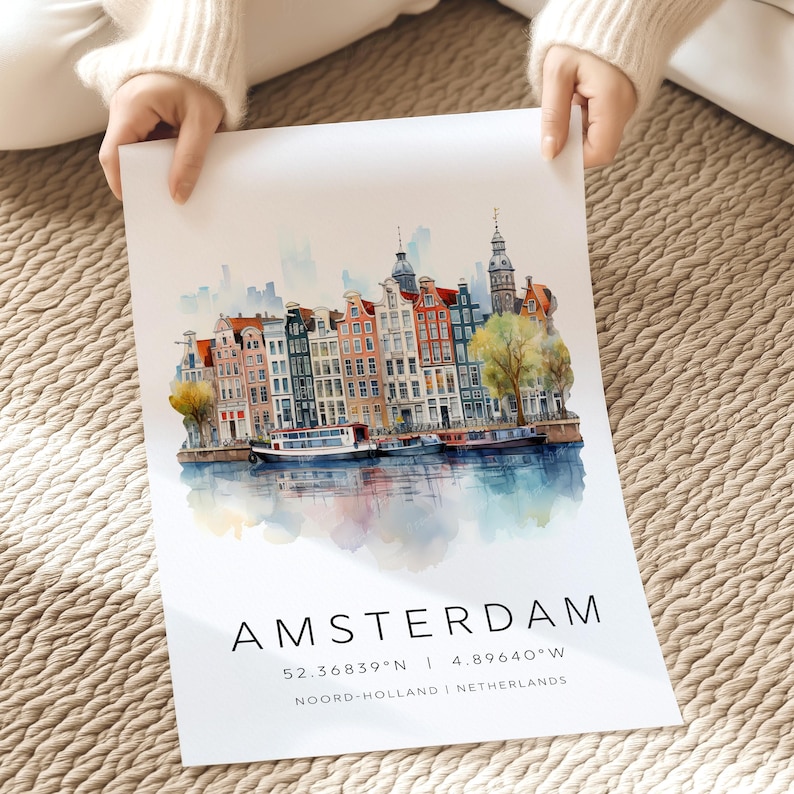 Peut inclure: Peinture &agrave; l'aquarelle d'Amsterdam, Pays-Bas, repr&eacute;sentant une ville avec des b&acirc;timents color&eacute;s et des bateaux sur un canal. La peinture comprend les coordonn&eacute;es 52.36839&deg;N | 4.89640&deg;W et le texte "Amsterdam, Noord-Holland, Pays-Bas".