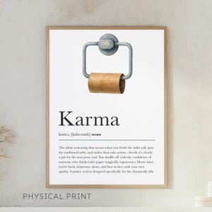 May include: Framed print with the word "Karma" and a definition. The image features a toilet paper roll holder with an empty cardboard tube. The text below describes the concept of karma in a humorous way.