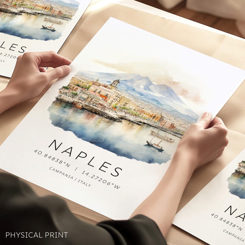 以下が含まれることがあります： ヴェスビオ山を背景に、イタリアのナポリを描いた水彩画。絵画には、建物、港、ボートのある街並みが描かれている。絵画の下には、「NAPLES 40.84838&deg;N 14.27206&deg;W CAMPANIA I ITALY」というテキストが印刷されている。