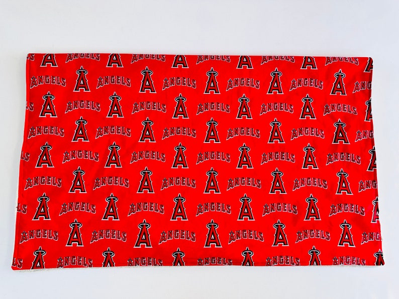 Puede incluir: Tela roja con un patr&oacute;n repetido de texto "Angels" blanco y un logotipo "A" estilizado.