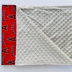 Puede incluir: Una manta para beb&eacute; roja y blanca con un patr&oacute;n de puntos minky gris en un lado y un lado rojo con las palabras "Angels" repetidas.