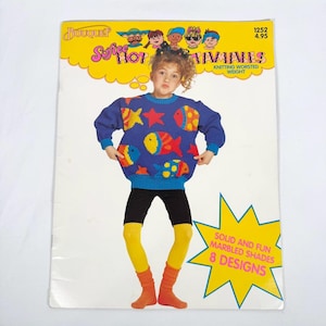 May include: A vintage knitting pattern booklet titled Bouquet Spice Hot Tamales featuring a blue long-sleeve jumper with colourful fish and star motifs. The cover displays a child wearing the jumper, black shorts, and yellow leggings, with text indicating knitting worsted weight and 8 designs.