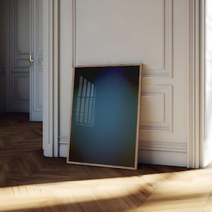 Könnte beinhalten: Ein rechteckiger Bilderrahmen mit hellem Holzfinish und einer dunklen, reflektierenden Glasoberfläche. Der Rahmen steht aufrecht und lehnt an einer weißen Wand mit Zierleisten, wobei sich ein dezentes blaues Licht darin spiegelt.
