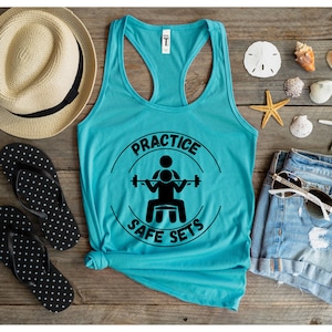 May include: A turquoise tank top with a black circle graphic that says "Practice Safe Sets" and a silhouette of a person lifting weights.