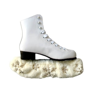 May include: White figure skates with a white faux fur boot cover with gold snowflake embellishments.