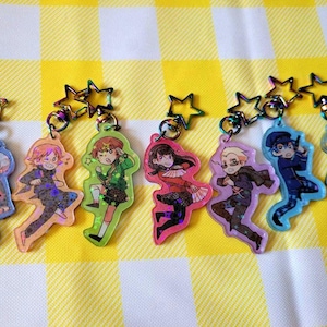 May include: Seven colourful character charms with iridescent glitter accents. Each charm features a different anime character with a star-shaped metal ring.