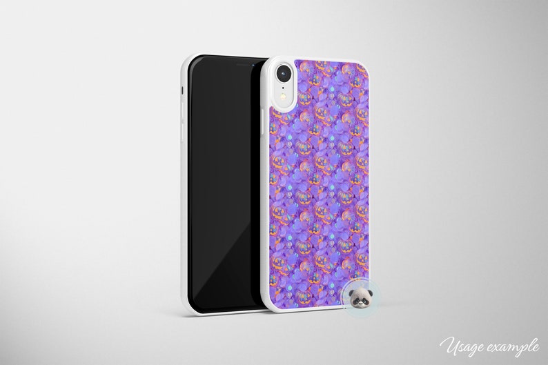 May include: A white phone case with a purple and orange pattern of jack-o'-lantern faces. The case is designed for a phone with a camera bump.