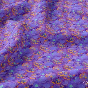 May include: Purple fabric with a repeating pattern of orange and yellow jack-o'-lantern faces and teal circles.