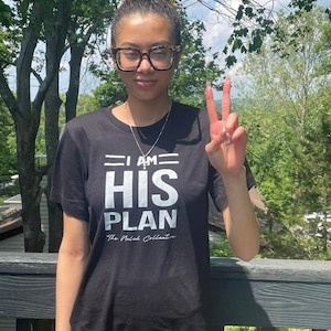 Puede incluir: Una camiseta negra con texto blanco que dice "I AM HIS PLAN The Nelah Collection".