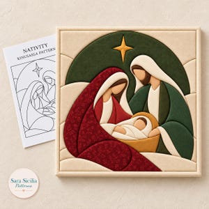 May include: A square Kinusaiga fabric art piece depicting a nativity scene with a central star, framed in light wood. Beside it lies a white paper instruction sheet titled NATIVITY KINUSAIGA PATTERN with a black line drawing of the scene.