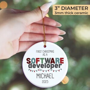 A hand holding a 3-inch diameter ornament with the text "FIRST CHRISTMAS AS A SOFTWARE DEVELOPER MICHAEL 2020" printed on it.
