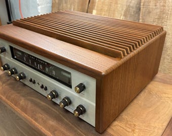 May include: A vintage wood-cased stereo receiver with a silver faceplate and a row of knobs. The receiver has a wood grain finish and the text "FM Stereo" is visible on the faceplate.