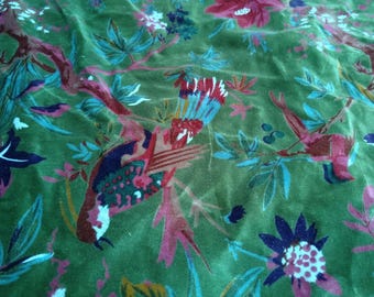 May include: Green velvet fabric with a floral and bird pattern. The design features red, pink, and blue flowers and birds on branches. The fabric has a soft, textured appearance.