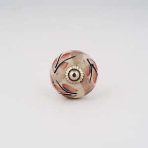 Op de afbeelding: Een keramische knop met een bloemenmotief in roze en witte tinten. De knop heeft een zilveren metalen basis.