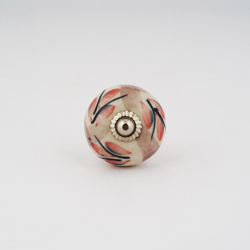 Op de afbeelding: Een keramische knop met een bloemenmotief in roze en witte tinten. De knop heeft een zilveren metalen basis.