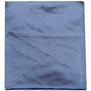 Puede incluir: Una funda de almohada cuadrada y plegada, de color azul apagado. La tela tiene un brillo sutil, lo que sugiere sat&eacute;n o seda. La funda de almohada est&aacute; cuidadosamente doblada, con una costura visible en el medio.