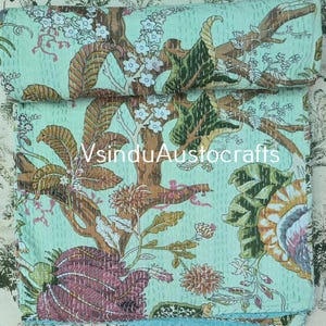 May include: A light mint green cotton quilt featuring a detailed botanical print with brown tree branches, dark green leaves, and large purple and yellow flowers. The fabric is covered in fine white running stitch kantha embroidery throughout.