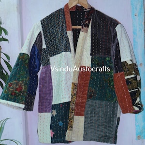 May include: A patchwork jacket in a variety of colours, including green, blue, purple, and white. The jacket has a V-neck and is hung on a wooden hanger. The text "VsinduAustocrafts" is visible on the jacket.