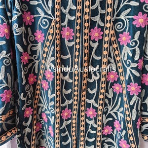 Op de afbeelding: Donkerblauwe geborduurde jas met roze bloemen en beige ranken. De jas heeft verticale perzik-gekleurde, kralenstrepen en bloemborduurwerk. De mouwen zijn aan de zijkanten zichtbaar. De tekst "VsinduAustocrafts" is zichtbaar.