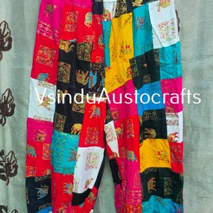May include: Patchwork trousers featuring a vibrant array of multicoloured fabric squares with elephant and floral patterns. The garment has an elastic waistband and elasticated cuffs at the ankles. The text VsinduAustocrafts is visible.