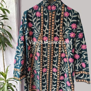 Op de afbeelding: Donkergroene geborduurde jas met roze bloemen en beige accenten. De jas heeft een hoge kraag en lange mouwen. De tekst "VsinduAustocrafts" is zichtbaar.
