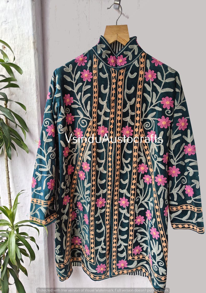 Op de afbeelding: Donkergroene geborduurde jas met roze bloemen en beige accenten. De jas heeft een hoge kraag en lange mouwen. De tekst "VsinduAustocrafts" is zichtbaar.