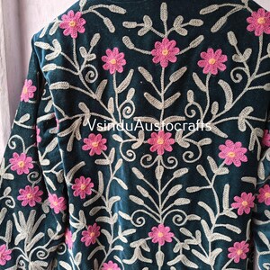 Op de afbeelding: Donkerblauwe jas met ingewikkelde bloemenborduurwerk. De jas heeft roze bloemen en zilvergrijze bladeren, waardoor een gedetailleerd patroon ontstaat. De mouwen en kraag zijn zichtbaar en tonen het vakmanschap. De tekst "VsinduAustocrafts" is zichtbaar.
