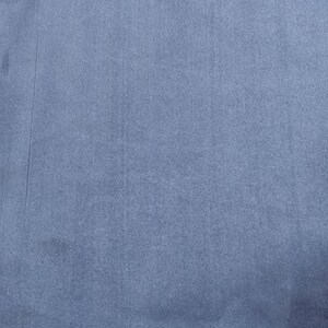 Puede incluir: Primer plano de una tela texturizada en un tono azul gris&aacute;ceo apagado. El material tiene una superficie sutil, ligeramente irregular, con l&iacute;neas verticales y peque&ntilde;as imperfecciones. El aspecto general es suave y mate.