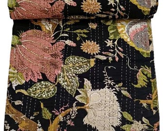 May include: Black floral quilt with large pink and cream flowers, green leaves, and yellow accents. The quilt is hand-stitched with white thread, and rolled up at the top.