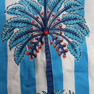 Può includere: Un tessuto a righe blu e bianche con un design di palma blu. La palma ha bacche rosse e foglie blu.