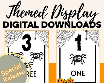 May include: Two printable Halloween-themed number cards with black numbers, spiders, and spiderwebs. The numbers are "1" and "3". The text "ONE" and "THREE" is also included. The cards are on a white background.