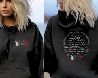 Könnte beinhalten: Schwarzer Kapuzenpullover mit einem weißen Salzstreuer, Rosmarin und einem Herz-Motiv auf der Vorderseite. Die Rückseite des Pullovers hat ein weißes Motiv mit dem Text "Werfe immer vergossenes SALZ über deine linke Schulter. Halte ROSMARIN an deinem Gartentor. Pflanze LAVENDEL für Glück und verliebe dich in die LIEBE, wann immer du kannst."