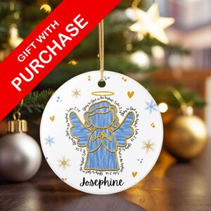 May include: White ceramic Christmas ornament featuring a blue angel design with gold accents. The ornament includes the name "Josephine" and the text "Glory to God in the highest - Luke 2:14". A gold string is attached for hanging.