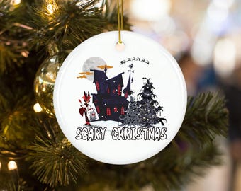 May include: A white ceramic Christmas bauble featuring a black and white illustration of a haunted house, a spooky Christmas tree, and a red devil holding a gift. The text "Scary Christmas" is printed below the illustration.