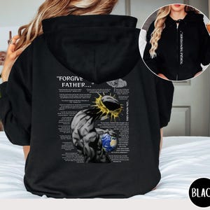 Könnte beinhalten: Schwarzer Kapuzenpullover mit Frontreißverschluss und Kapuze. Auf der Rückseite befindet sich eine Grafik einer Figur mit Dornenkrone, einem Globus und dem Text "FORGIVE FATHER..." und andere Bibelverse. Der Kapuzenpullover ist schwarz.