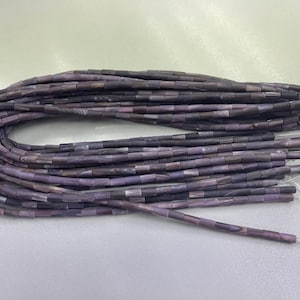 May include: Strands of rectangular beads in shades of purple, grey, and brown. The beads are strung together on thin, clear cords. The beads are small and uniform in size, creating a textured appearance. Ideal for jewellery making.