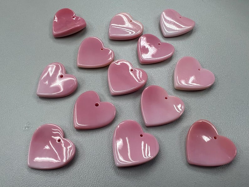 Puede incluir: Una colecci&oacute;n de 13 botones de concha de coraz&oacute;n rosa. Los botones son de diferentes tama&ntilde;os y tienen un acabado liso y pulido.