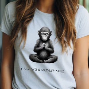 May include: A gray t-shirt with a black and white illustration of a monkey meditating. The text "Calm your monkey mind" is printed below the monkey.