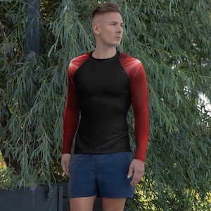 May include: A black long-sleeve shirt with red sleeves and white accents radiating from the shoulders. The shirt is form-fitting and appears to be made of a stretchy material. The person in the image is wearing blue shorts.