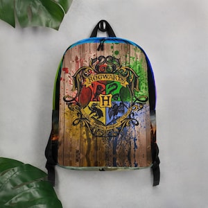 May include: A Hogwarts themed backpack with a wooden background and colorful paint splatters. The Hogwarts crest is featured in the center with the four house crests and the words "Hogwarts" above.