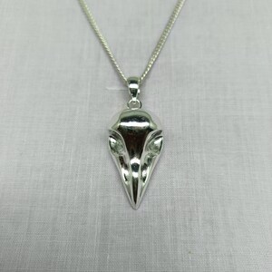 Puede incluir: Un collar con un colgante de plata con un dise&ntilde;o detallado de cr&aacute;neo de p&aacute;jaro. El colgante tiene la forma de una cabeza de p&aacute;jaro con un pico puntiagudo y detalles intrincados de los ojos.
