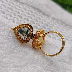 May include: Gold ring featuring a heart-shaped green and white agate stone. The ring is open and has a heart-shaped design on the band.