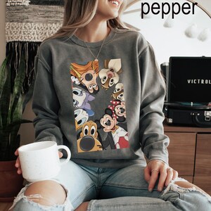 May include: A grey sweatshirt with a vibrant graphic of cartoon characters such as Mickey and Minnie Mouse. The sweatshirt has a crew neck and a relaxed fit. The word "pepper" is written in white at the top.