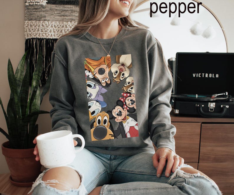 May include: A grey sweatshirt with a vibrant graphic of cartoon characters such as Mickey and Minnie Mouse. The sweatshirt has a crew neck and a relaxed fit. The word "pepper" is written in white at the top.